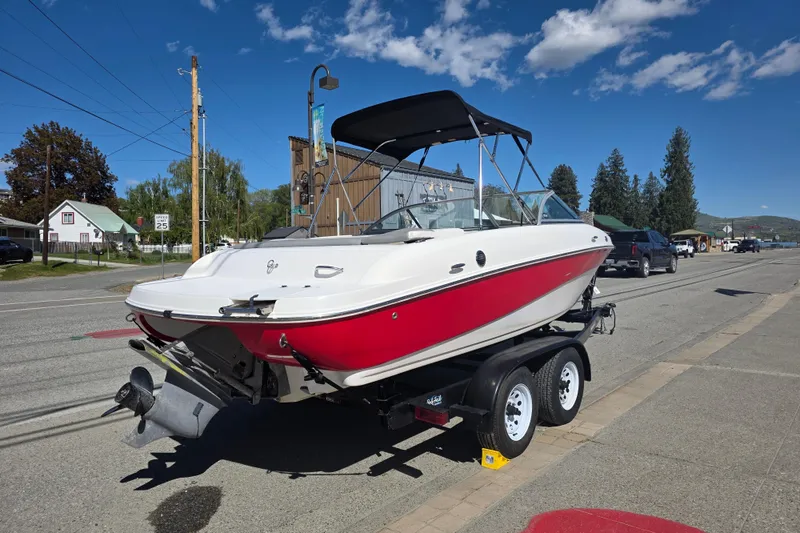 Slide: The Image of 2014 Reinell 207 LS boat on trailer, parked on street under clear blue sky. - 2