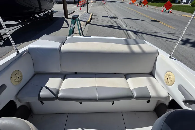 Slide: The Image of 2014 Reinell 207 LS boat interior with white and gray seating, parked on a street. - 5