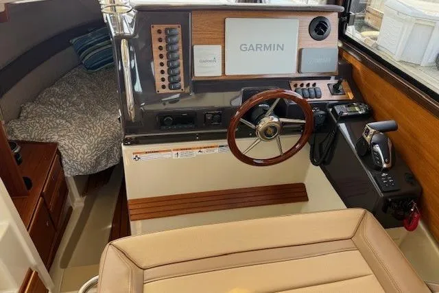 Slide: The Image of 2023 Ranger Tugs R-27 helm with Garmin navigation, wood accents, and cozy cabin interior. - 13