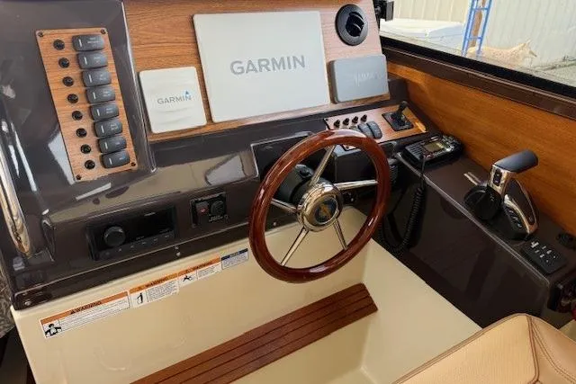 Slide: The Image of 2023 Ranger Tugs R-27 helm with Garmin navigation, wood accents, and steering wheel. - 14