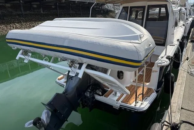 Slide: The Image of 2023 Ranger Tugs R-27 with inflatable boat on stern, docked in marina. - 20