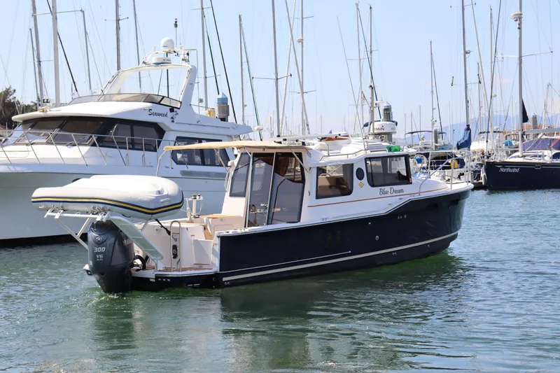 Slide: The Image of 2023 Ranger Tugs R-27 boat docked in a marina, surrounded by sailboats. - 3