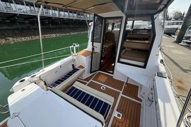 Slide: The Image of 2023 Ranger Tugs R-27 boat interior with seating and wood flooring at a marina. - 6