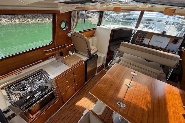 Slide: The Image of Interior of 2023 Ranger Tugs R-27 boat with wood finish, kitchen, and navigation equipment. - 9