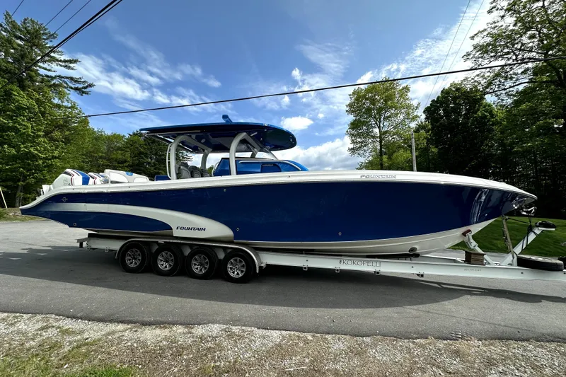 The Image of 2023 Fountain 43 NX boat on trailer, blue and white design, parked outdoors. - 0
