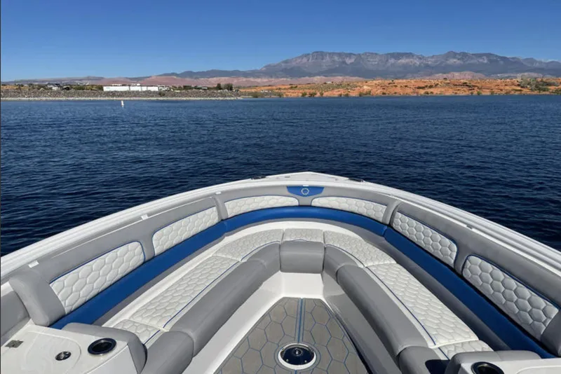 Slide: The Image of Bow view of 2023 Fountain 43 NX boat on a serene lake with mountain backdrop. - 7