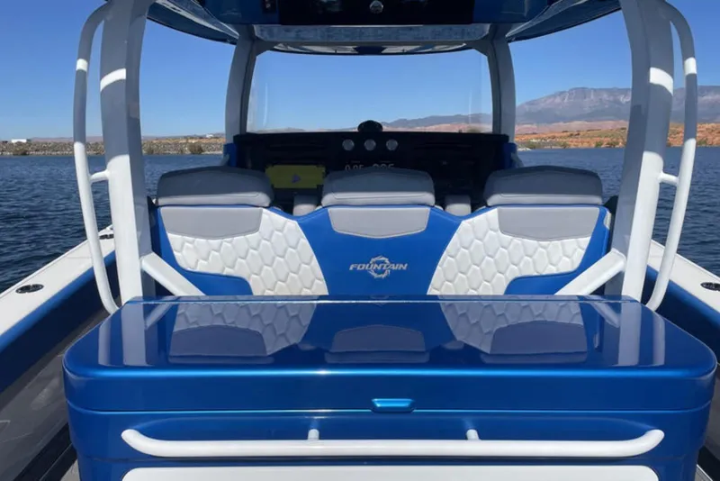Slide: The Image of 2023 Fountain 43 NX boat interior with blue and white seating on a lake. - 8