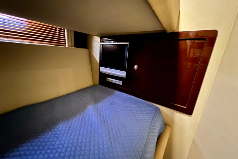 Slide: The Image of Cozy cabin interior of 2007 Sea Ray 58 Sedan Bridge with TV and blue bedding. - 118