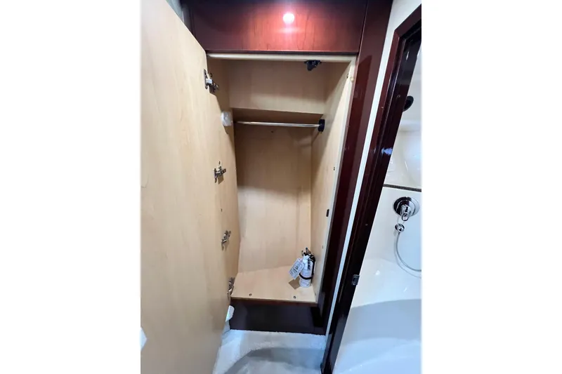 Slide: The Image of Open wooden closet inside 2007 Sea Ray 58 Sedan Bridge yacht, featuring hanging rod and shelf. - 126