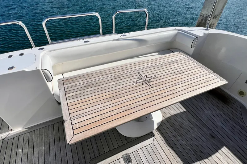 Slide: The Image of 2007 Sea Ray 58 Sedan Bridge yacht deck with wooden table and seating area. - 30