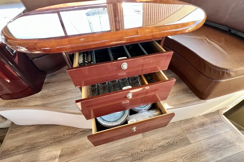Slide: The Image of Interior of 2007 Sea Ray 58 Sedan Bridge with open wooden drawers and seating area. - 85