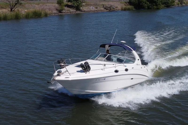 The Image of 2005 Sea Ray Sundancer 280 cruising on a serene river, creating gentle waves. - 1