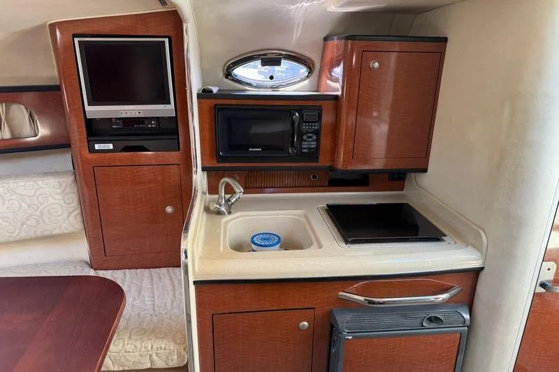 Slide: The Image of 2005 Sea Ray Sundancer 280 interior kitchen with microwave, sink, and TV. - 10