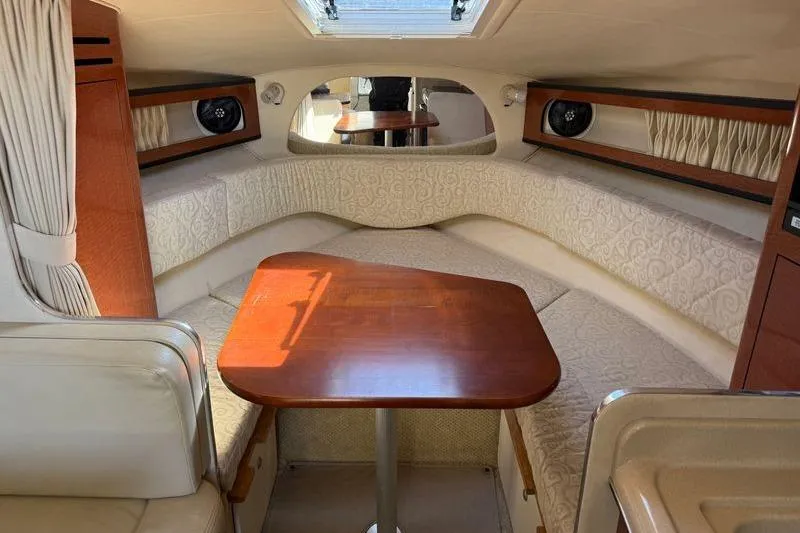 Slide: The Image of 2005 Sea Ray Sundancer 280 cabin interior with wood table and cushioned seating. - 11