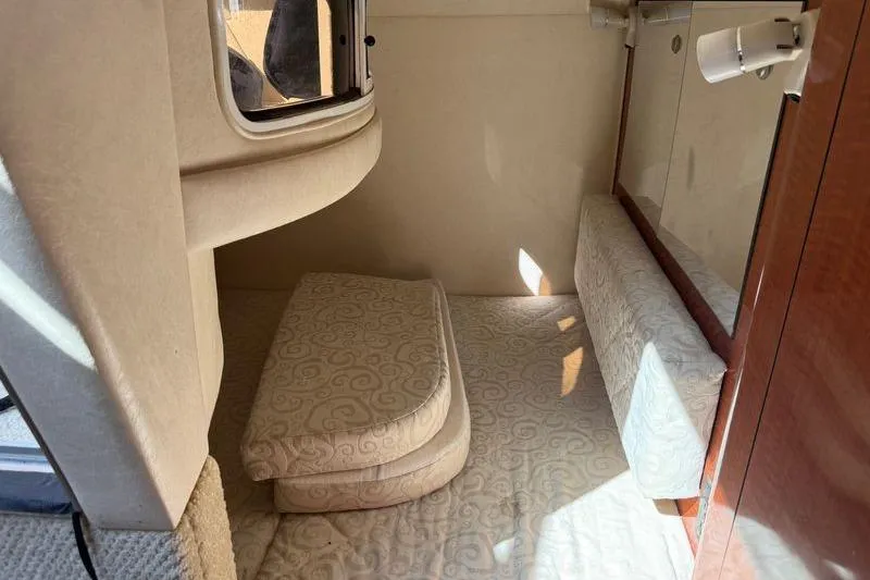 Slide: The Image of 2005 Sea Ray Sundancer 280 cabin interior with beige upholstery and compact sleeping area. - 12