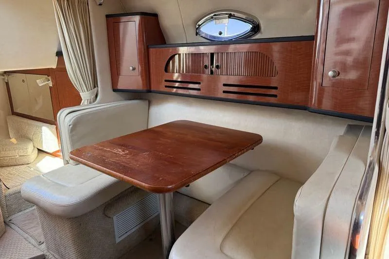Slide: The Image of Interior of 2005 Sea Ray Sundancer 280, featuring a cozy dining area with wooden table. - 9