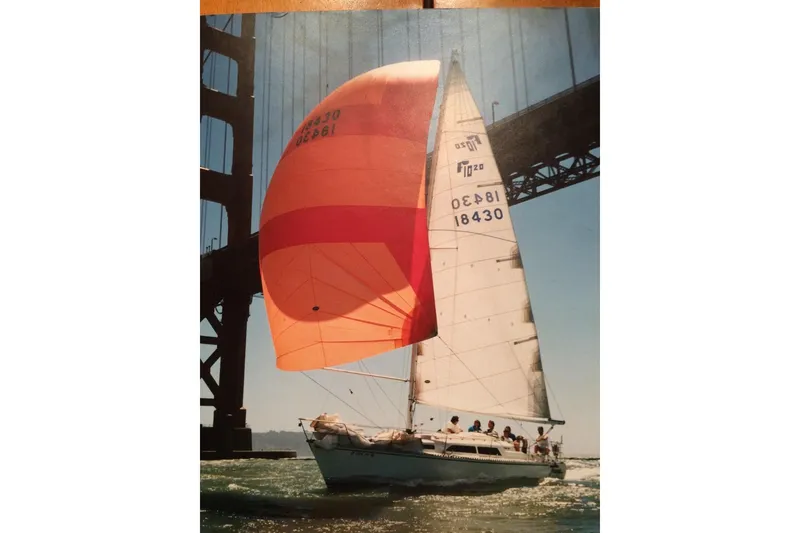 Slide: The Image of Sailboat Farr 1020 (1986) with orange spinnaker under a bridge on a sunny day. - 3