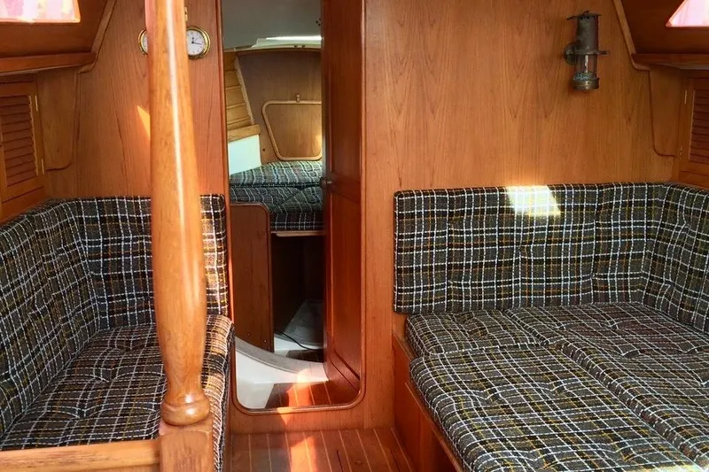 Slide: The Image of Interior of 1986 Farr 1020 sailboat with plaid seating and wooden paneling. - 7