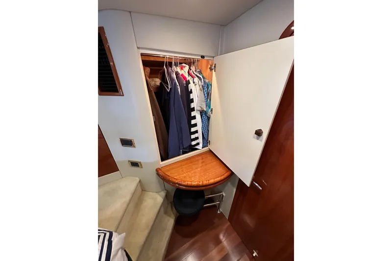 Slide: The Image of Wardrobe inside 2000 Sunseeker Predator 60 yacht, featuring hanging clothes and wooden accents. - 107