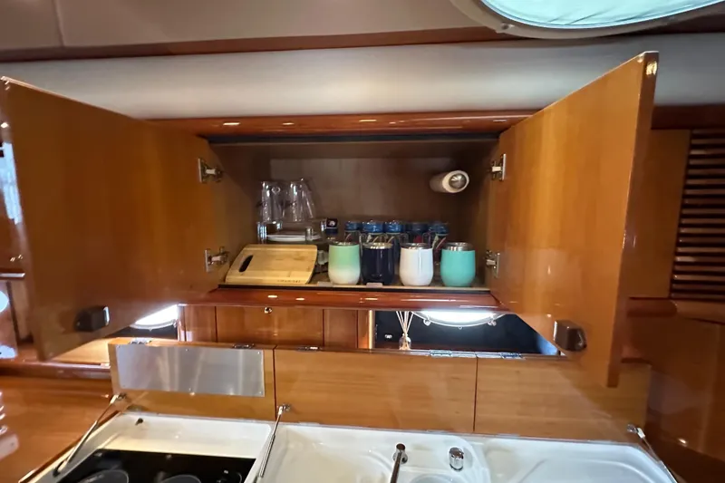 Slide: The Image of Open wooden cabinet in Sunseeker Predator 60 yacht kitchen, displaying cups and glasses. - 89