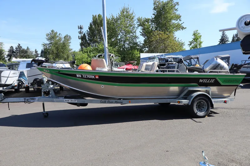 Slide: The Image of 1997 Willie Boats Predator on trailer, parked outdoors, surrounded by trees and other boats. - 6