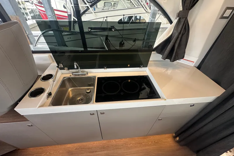 Slide: The Image of Modern kitchen area in 2023 Beneteau Antares 11 Coupe yacht, featuring sink and stove. - 11