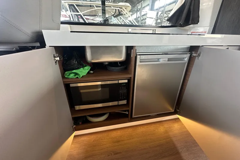 Slide: The Image of 2023 Beneteau Antares 11 Coupe kitchen with microwave, fridge, and storage cabinets. - 21