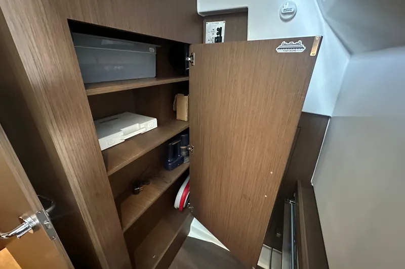 Slide: The Image of Wooden storage cabinet inside 2023 Beneteau Antares 11 Coupe boat, featuring shelves and various items. - 26