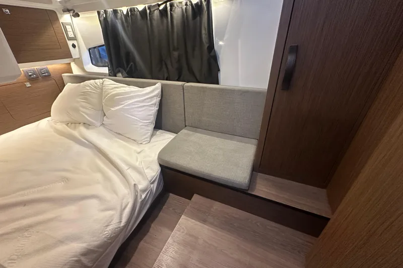 Slide: The Image of 2023 Beneteau Antares 11 Coupe cabin interior with bed, cushions, and wooden accents. - 32