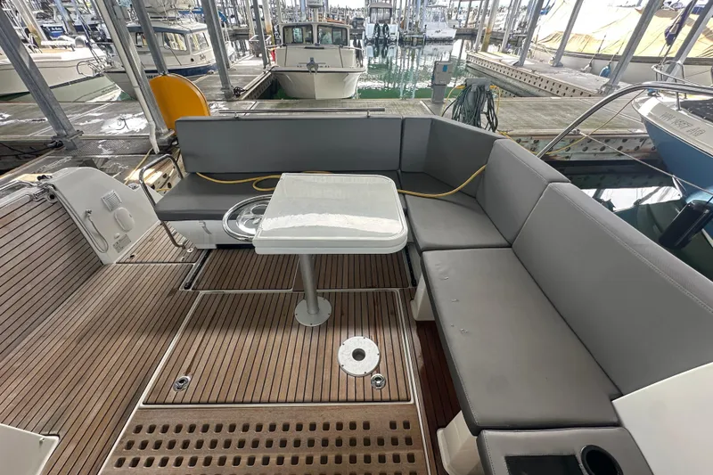 Slide: The Image of 2023 Beneteau Antares 11 Coupe cockpit with gray seating and wooden deck at marina. - 39