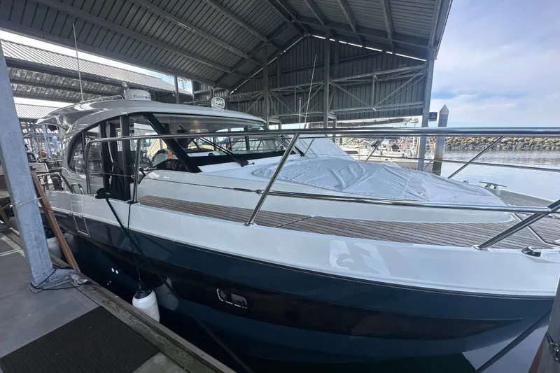 Slide: The Image of 2023 Beneteau Antares 11 Coupe docked under a covered marina, showcasing sleek design. - 46