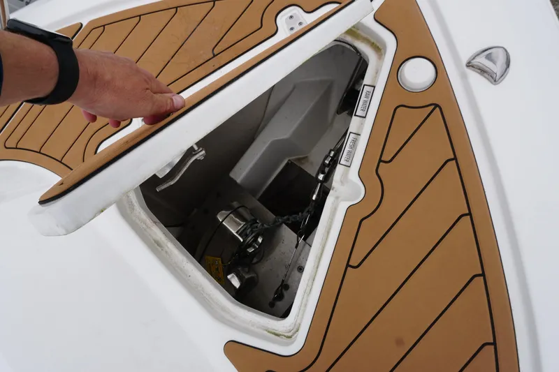 Slide: The Image of 2021 Pursuit OS 325 Offshore boat hatch with teak flooring and visible anchor mechanism. - 12