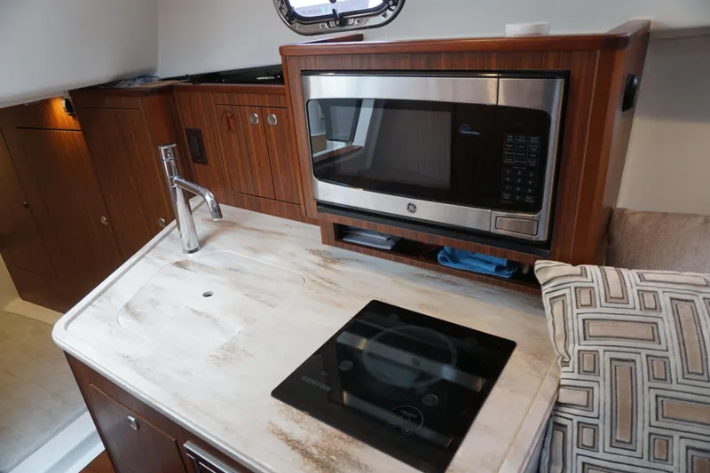 Slide: The Image of 2021 Pursuit OS 325 Offshore yacht interior with microwave, sink, and stove in compact kitchen. - 15