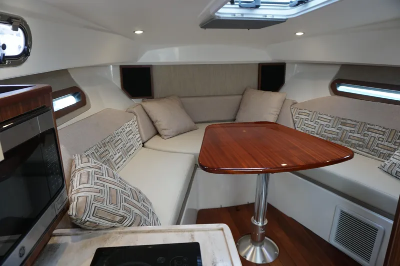 Slide: The Image of 2021 Pursuit OS 325 Offshore cabin with elegant seating and wooden table. - 16