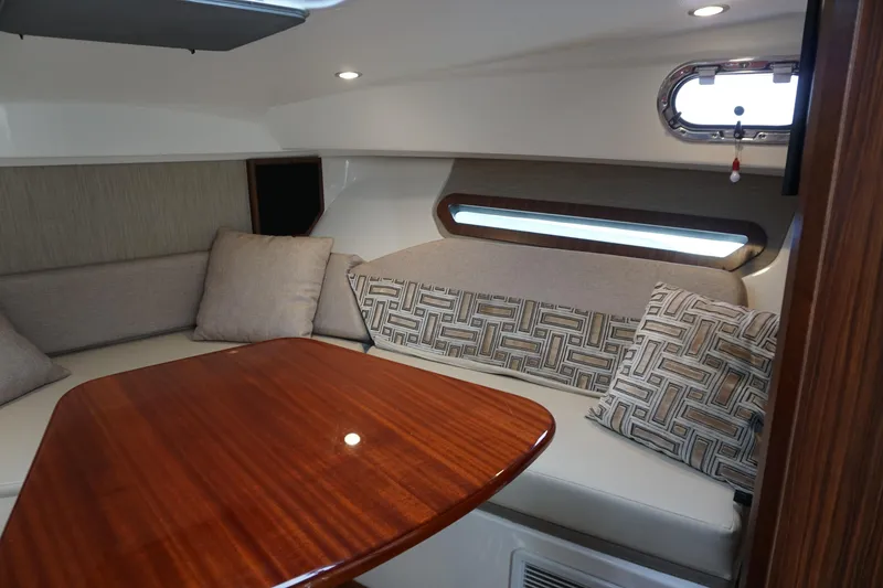 Slide: The Image of 2021 Pursuit OS 325 Offshore cabin interior with wooden table and cushioned seating. - 18