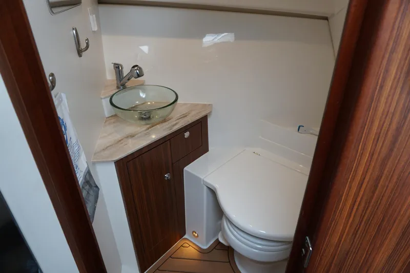 Slide: The Image of 2021 Pursuit OS 325 Offshore boat bathroom with glass sink and wooden cabinetry. - 20
