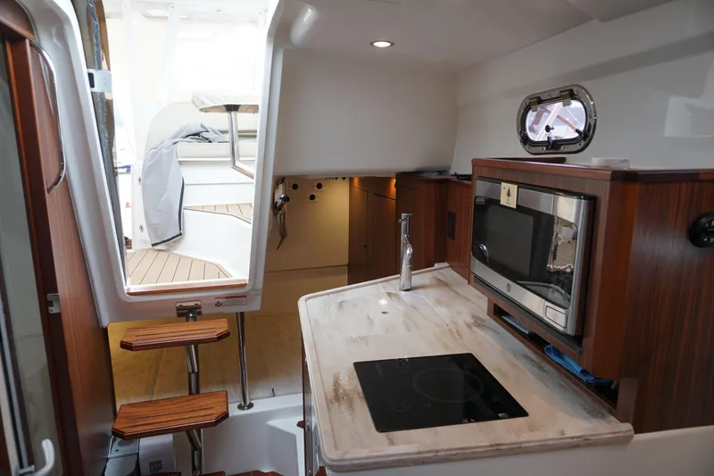 Slide: The Image of 2021 Pursuit OS 325 Offshore boat interior with kitchenette and stairs. - 24