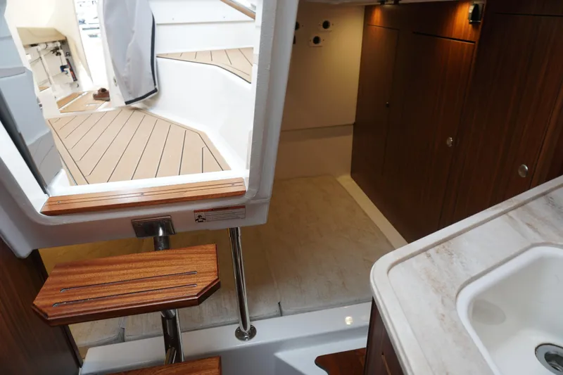 Slide: The Image of Interior view of 2021 Pursuit OS 325 Offshore boat, featuring wooden steps and cabinetry. - 26
