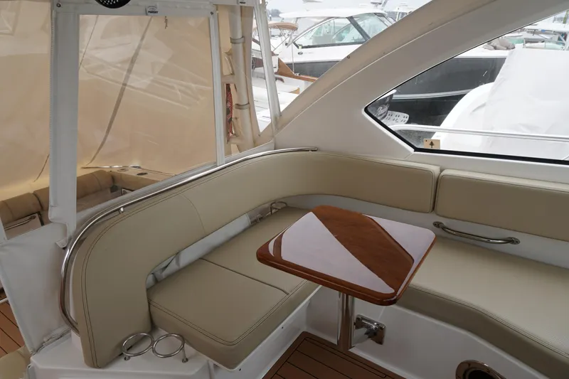 Slide: The Image of 2021 Pursuit OS 325 Offshore boat interior with beige seating and wooden table. - 38