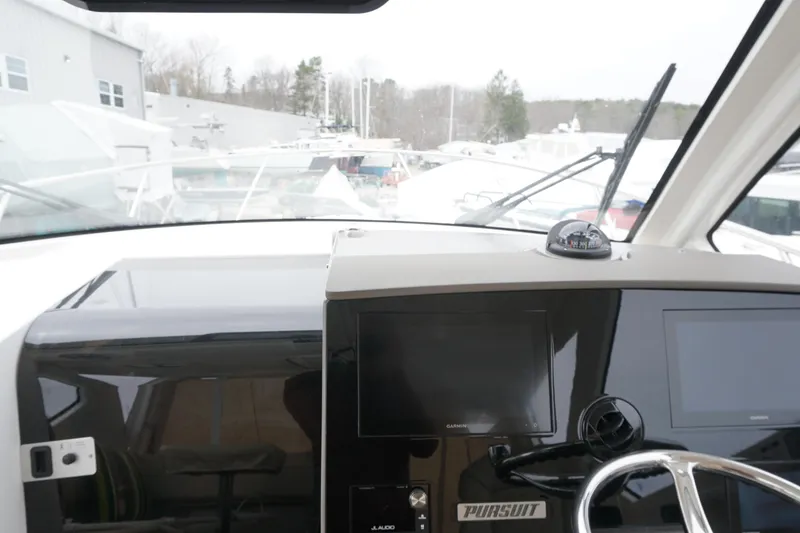 Slide: The Image of 2021 Pursuit OS 325 Offshore boat dashboard with navigation screens and steering wheel. - 4