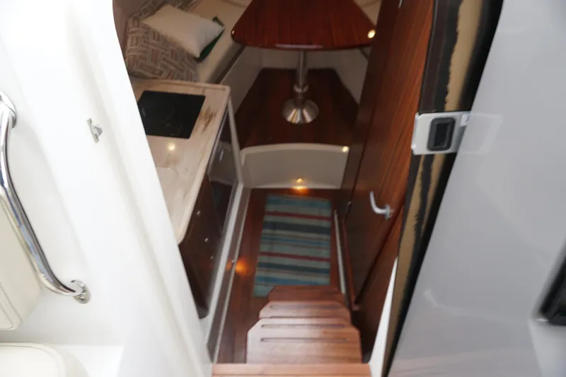 Slide: The Image of Interior view of 2021 Pursuit OS 325 Offshore boat cabin with wood finishes. - 5