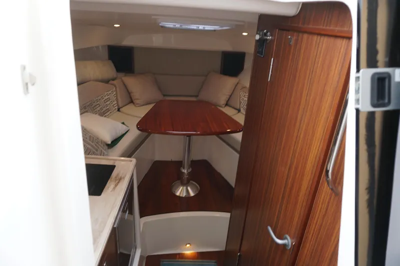 Slide: The Image of 2021 Pursuit OS 325 Offshore cabin interior with wooden table and cushioned seating. - 6