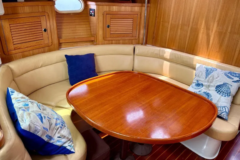 Slide: The Image of Cozy dining area in 2000 Catalina 42 MkII sailboat with wooden table and cushioned seating. - 10