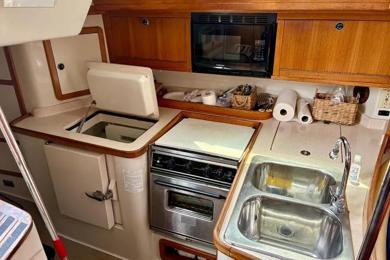 Slide: The Image of 2000 Catalina 42 MkII yacht kitchen with stove, sink, and wooden cabinetry. - 9