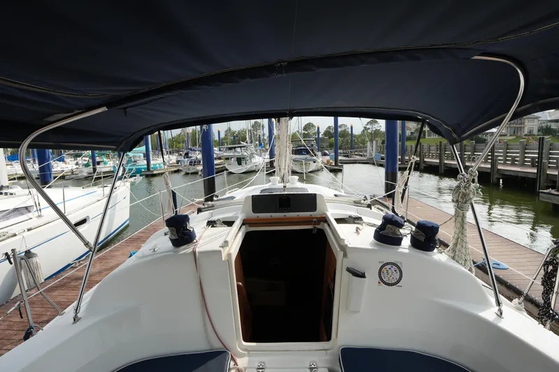 Slide: The Image of 1997 Hunter 336 sailboat cockpit view at marina, featuring covered seating area. - 9