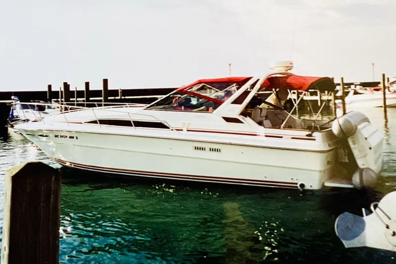 The Image of 1989 Sea Ray 340 Express Cruiser docked in a marina with red canopy. - 0