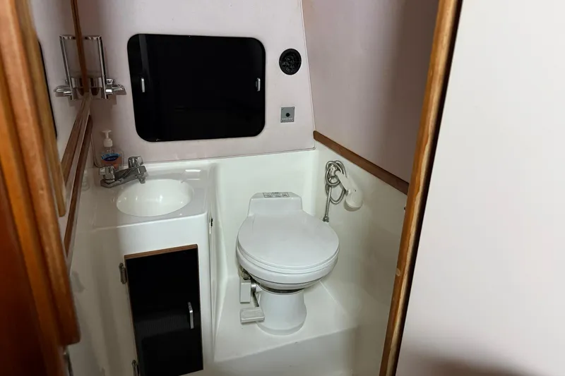 Slide: The Image of 1989 Sea Ray 340 Express Cruiser bathroom with sink, toilet, and mirror. - 11