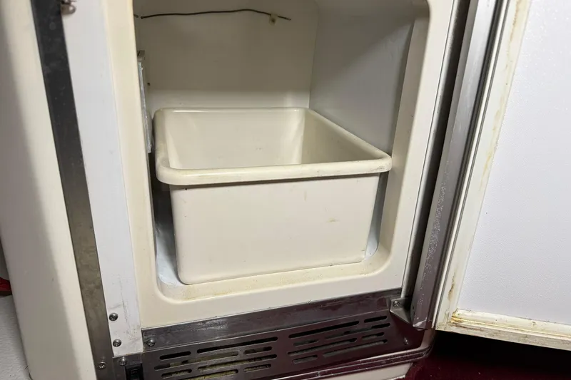 Slide: The Image of Open refrigerator compartment on 1989 Sea Ray 340 Express Cruiser, featuring a white storage bin. - 22