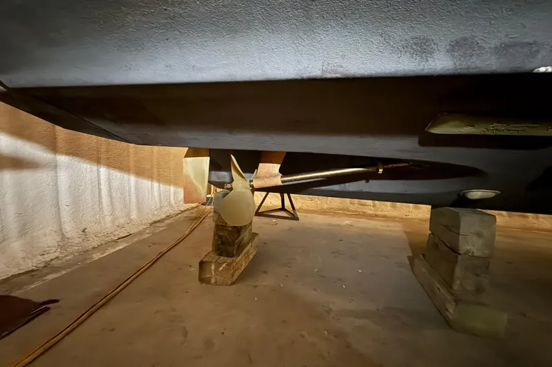 Slide: The Image of 1989 Sea Ray 340 Express Cruiser underside with propeller and shaft, supported on blocks. - 3