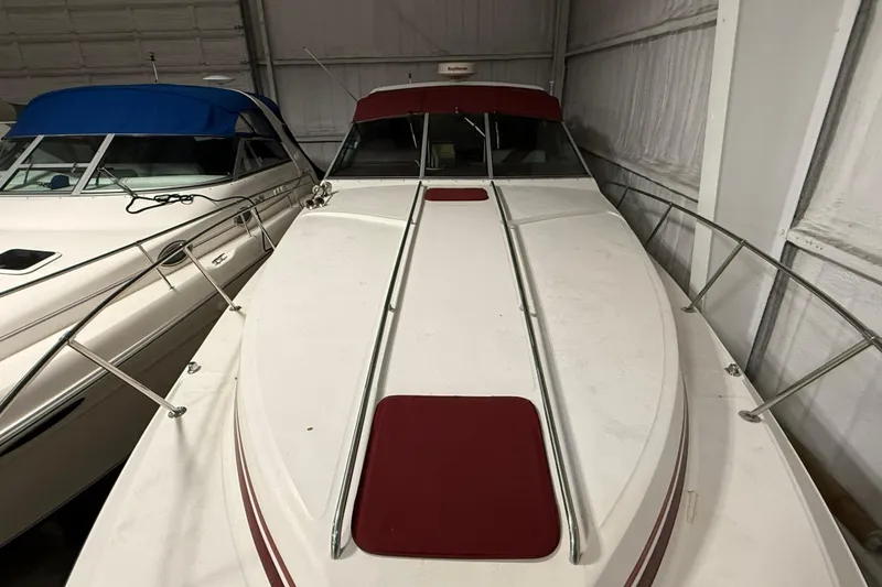 Slide: The Image of 1989 Sea Ray 340 Express Cruiser with red accents, docked indoors. - 32
